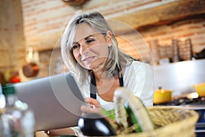 Portrait of woman in kitchen checking recipe on internet