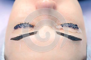 Portrait of woman on lash lifting laminating and eyebrow painting, top view.