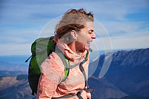 Portrait of a woman laughing in the mountains, with her hair blowing in the wind. Hiker girl in the Carpathian mountains