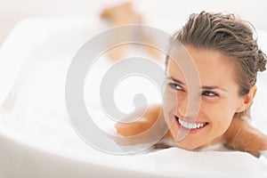 Portrait of woman laying in bathtub and looking on copy space