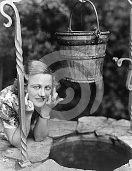 Portrait of a woman leaning on a well with her finger crossed