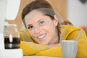 portrait woman leaning on worktop by coffee machine