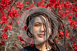 Portrait of woman with locs shot against colorful flowers