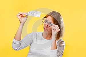 Portrait of woman looking at the dollar bill checking for falsity. Yellow background. The concept of checking counterfeit money photo
