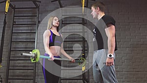 Portrait of woman and man lifting barbells during a gym workout at fitness center