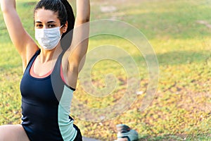 Portrait of a woman with a mask doing a yoga pose in a park