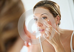 Portrait of a woman in the mirror applying a cream