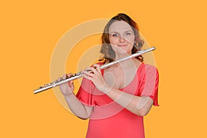 Portrait of a woman musician with a flute on a studio yellow background. Flutist with a large concert transverse flute in her