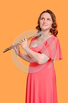Portrait of a woman musician with a flute on a studio yellow background. Flutist with a large concert transverse flute in her
