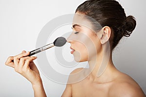 Close-up of young woman naked shoulders applying make up for a evening date in front of a camera. Space for text. photo