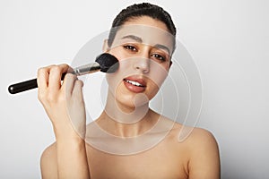 Close-up of young woman naked shoulders applying make up for a evening date in front of a camera. Space for text. photo