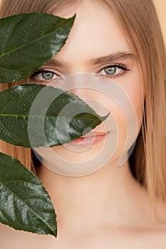 Portrait woman with natural green leaf, blond model girl with clear skin face. Concept Fashion flora beauty