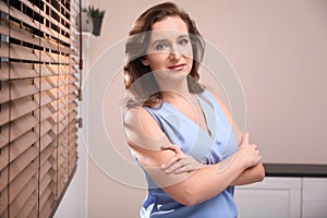 Portrait of woman near window with blinds