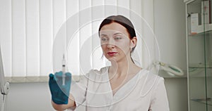 Portrait of woman nurse holding a syringe in hands isolated on white. Female doctor prepares an injection for a patient