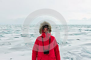 Portrait of a woman in a parka jacket with a fur hood in a snowy Baikal in hummocks