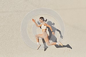 Portrait of woman with perfect body jumping over in the air, wearing white top and beige leggins, doing sports exercises outdoor,