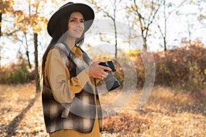 Portrait of woman photographer taking pictures in natural landscape in autumn park or forest