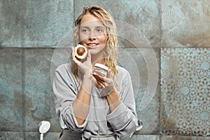 Portrait of woman with piece of avocado and regenerating face cream. Clean soft Skin, healthy