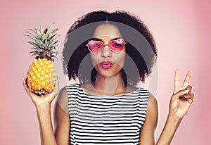 Portrait, woman and pineapple with peace, studio and detox food on pink background. Nutrition, fruit and eyewear for