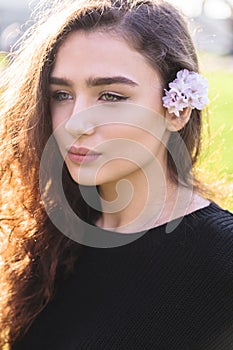 Portrait of woman with pink flower behind her ear photo