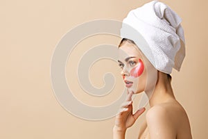 portrait woman pink patches on the face with a towel on the head beige background