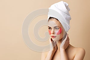 portrait woman pink patches on the face with a towel on the head beige background