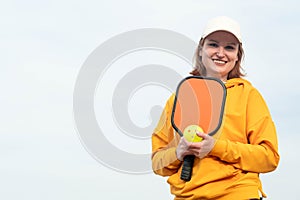 portrait woman player pickleball game over blue sky, pickleball yellow ball with paddle, outdoor sport leisure activity.