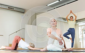 Portrait of woman practicing yoga in group, making twisting asana