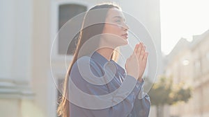 Portrait of woman praying with closed eyes to God asking for blessing, help, forgiveness outdoors