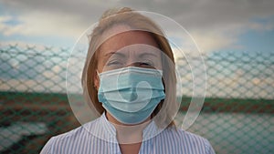 Portrait of woman in a protective medical mask and standing in the street. Safety mask on woman face. Social distance on