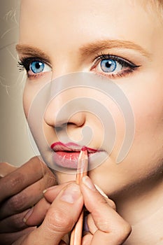 Portrait of a woman putting on lip liner.