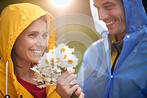 Portrait of a woman receiving a bouquet of flowers from a man; Love on a rainy day concept