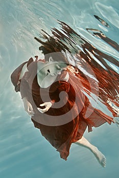 Portrait of a woman in a red dress floating underwater