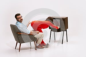 Portrait of woman in red pyjama turning off TV in front of her husband. Need of attention