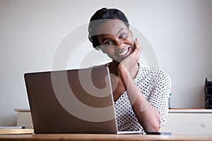 Woman resting head on hand sitting at desk with laptop photo