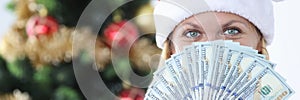 Portrait of woman in santa claus hat holding fan with cash american dollars