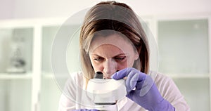 Portrait of woman scientist biologist doctor looks into laboratory microscope