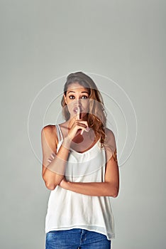 Portrait, woman and secret with finger on lips in studio for hush, news or quiet sign isolated on a white background