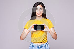 Portrait of a woman showing blank smartphone screen over gray background