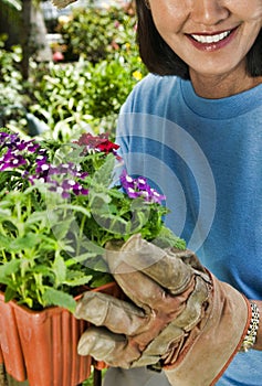 Portrait of woman showing potted flower in the garden