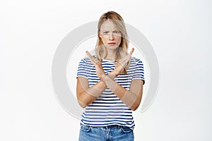 Portrait of woman showing stop sign, showing crossed arms gesture, prohibit action, rejecting smth with angry serious