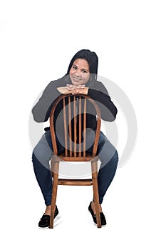 Portrait of a woman sitting on a chair in white background, hand on hip