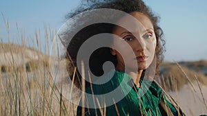 Portrait woman sitting sand looking camera. Dreamy girl enjoying landscape.