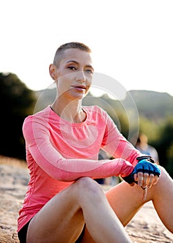 Portrait of woman sitting on the top of cliff in the park  after exercise