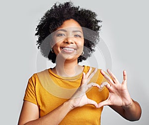 Portrait, woman and smile with heart hands in studio, white background and care of kindness, emoji and icon. Happy young