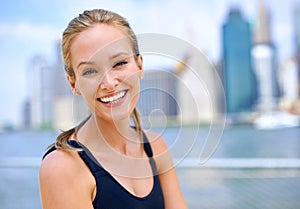 Portrait, woman and smile at river side with city view on sport clothes to jog, fitness and healthy mindset in New York