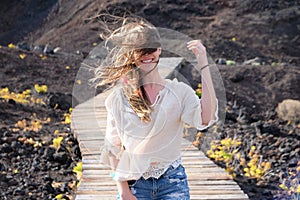 Portrait of a woman smiling with long blonde hair all over her faceGirl walking on windy wooden path with hair on her face