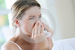 Portrait of a woman sneezing and blowing her nose