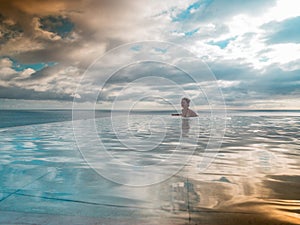 Portrait of a woman standing in an infinity pool looking over the sea