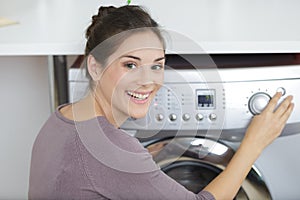 Portrait woman starting washing machine